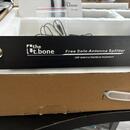 Černý kovový přístroj s nápisy the t.bone, Free Solo Antenna Splitter a UHF Antenna Distribute Implement. Na levé straně je vidět jeden koaxiální kon…