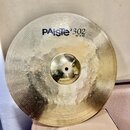 Zlatý kovový činel s viditelným rýhováním povrchu. Na horní části je černý nápis PAiste 302 a pod ním menší text 20" Ride. Povrch vykazuje drobné škr…