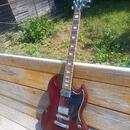 Tmavě červená elektrická kytara s černým pickguardem a hnedým hmatníkem. Na hlavě je zlatý nápis Gibson. Nástroj má dva humbuckery, čtyři ovládací kn…