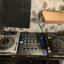 Sada DJ equipmentu složená ze dvou stříbrno-černých přehrávačů a jednoho černého mixeru. Na přehrávačích je nápis Pioneer a modelové označení CDJ-850…