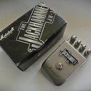 Stříbrný efekt pedál s kovovým povrchem a černou krabicí. Na pedálu i na krabici je nápis THE JACKHAMMER JH-1 a logo Marshall. Pedál má tři ovládací…