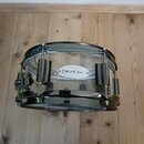 Průhledný malý buben s chromovanými obručemi a hardwarem. Na korpusu je umístěno logo s nápisem DRUM CRAFT. Nástroj vykazuje známky běžného používání…