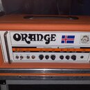 Kytarový kombozesilovač v oranžovém vinylu s bílým předním panelem. Na panelu je velký nápis ORANGE, vlajka Islandu a barevný znak. Ovládací prvky js…