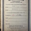 Fotografie znázorňuje papírový certifikát pravosti s nápisem Certificate of Authenticity a logem Eastman HANDCRAFTED GUITARS & MANDOLINS. V dokumentu…