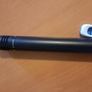 Černý kovový předmět válcovitého tvaru s žebrovaným koncem. Na povrchu je viditelný nápis AUTHENTICA. Povrch je matný s drobnými stopami používání.