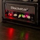 Černý kytarový kombozesilovač značky Blackstar z řady HT MkII. Na předním panelu jsou bílé a zelené ovratové knofíky s popisky POWER, REVERB LEVEL, E…