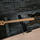 Černá elektrická basová kytara v černém polstrovaném kufru. Na hlavě hmatníku je nápis MUSICMAN StingRay. Nástroj má světlý dřevěný krk a hmatník s č…
