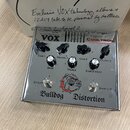 Stříbrný efekt pedál s nápisem Bulldog Distortion a logem hlavy buldoka. Na horním panelu je značka VOX a nápis COOLTRON TUBE TECHNOLOGY. Zařízení má…