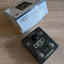 Černý efekt pedál s nápisy DITTO LOOPER a tc electronic. Na horní straně jsou ovládací prvky: otočný knoflík LOOP LEVEL, spínače FX a STOP s nápisem…