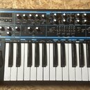 Černý MIDI kontrolér s bílými a černými klávesami. Na ovládacím panelu je nápis novation a řada knoflíků, posuvníků a tlačítek s popisy jako EFFECTS,…