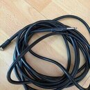 Černý instrumentální kabel s konektory typu jack. Na jednom z konektorů je viditelný bílý nápis "TAMA". Kabel je svinutý do klubíčka a položený na sv…