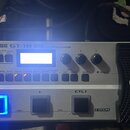 Stříbrný basový efektový procesor s černým pedálem a ovládacími prvky. Na horní hraně je nápis BOSS GT-1B BASS EFFECTS PROCESSOR a vpravo dole logo C…