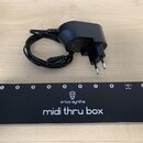 Černý obdélníkový modul s nápisy erica synths a midi thru box. Na horní hraně se nachází osm očíslovaných vstupů, konektor s označením 9V DC a vstup…