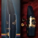 Na fotografii je modrý saxofonový munční kus s mosazným stiskovacím prstencem a krabička. Na krabičce jsou nápisy BLUE EBONITE, SAX. ALTO Mib - Eb a…