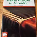 Fotografie znázorňuje obal notové knihy s názvem „Balkan Melodies for Accordion“ od autora By Dr. Frances M. Irwin. V horní části je nápis „Mel Bay P…