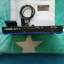 Modrý kytarový procesor s bílým nápisem BOSS GT-1. Na zadní straně jsou viditelné vstupy a výstupy s popisky INPUT, AUX IN, PHONES, OUTPUT L, OUTPUT…