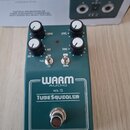 Zelený kytarový efekt s bílým nápisem WARM AUDIO, WA-TS a TUBE SQUEALER. Pedál má čtyři černé kontrolní knoflíky s popisky DRIVE, LEVEL, MIX a TONE o…