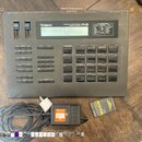 Šedý rytmický automat Roland HUMAN RHYTHM COMPOSER R-8 s digitálním displejem a gumovými pady. Zařízení má v horní části posuvníky VOLUME a VALUE a ř…