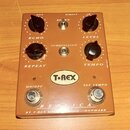 Hnědý efekt pedál s nápisem REPLICA a logem T-REX engineering. Obsahuje čtyři černé otočné ovladače s popisky OUT, IN, ECHO (REPEAT) a LEVEL (TEMPO),…