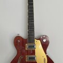 Tmavě červená polodublová elektrická kytara s dvěma f-otvory a žlutobílým pickguardem. Na hlavě je nápis GRETSCH a na pickguardu je logo GRETSCH. Nás…
