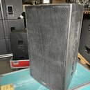 Černý koncertní reproduktor v bedně s texturovaným povrchem a kovovou mřížkou. Na spodní liště mřížky je malý nápis "dB technologies". Povrch bedny v…