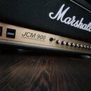 Kytarový zesilovač značky Marshall v černé barvě s kovovým předním panelem. Na panelu je uveden model JCM 900 a nápis 100W Hi Gain Dual Reverb. Jsou…