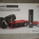 Fotografie znázorňuje krabici s produktem Scarlett 2i2 Studio. Na obalu je zobrazen set obsahující červené audio rozhraní s nápisy Focusrite a Scarle…