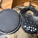 Černý elektronický bicí pad s kulatou hrací plochou a ovládací modul. Na modulu je bílý nápis ION, PRO SESSION DRUMS a digitální displej se třemi čís…