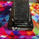 Černý volume pedál s gumovou protiskluzovou plochou. Na spodní části je bílý nápis Volume a pod ním menší nápis stereo. V horní části pedálu je nečit…