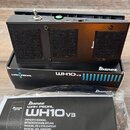 Černý wah pedál značky Ibanez, model WH10v3. Je umístěn na své originální krabici s nápisy Ibanez, WAH PEDAL a WH10v3. Před pedálem je v plastovém ob…