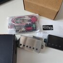 Fotografie zobrazuje sadu elektroniky pro kytaru značky EMG. Soubor obsahuje černý a stříbrný kovový modul s nápisem EMG, plastový sáček s kabeláží a…