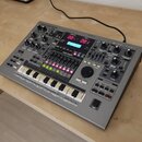 Šedý sekvenční workstation Roland MC-505 s nápisem groovebox v pravém horním rohu. Zařízení má digitální displej s červenými číslicemi 001 a 001, zah…