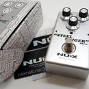 Stříbrný kytarový efekt pedál s nápisy „STEEL SINGER“ a „DRIVE“. Na spodní části je logo NUX a text Reissue Series. Pedál má dva černé ovládací knofl…