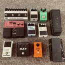 Fotografie zobrazuje skupinu efektů pro kytaru. V horní řadě jsou bílý pedál Fender SHIELDS BLENDER, béžový Digital Delay a zelený Ibanez TUBE SCREAM…