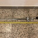Fotografie zobrazuje chromovaný kovový stojan nebo držák s teleskopickým hřídelem. Na pravé straně je mechanismus s několika utahovacími šrouby a čer…