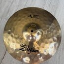 Zlatavý kovový činel s výrazným klepaným povrchem. Na povrchu jsou černé nápisy „A POCKET HIHAT BOTTOM 12"“ a logo „Avid Zildjian“. Povrch vykazuje d…