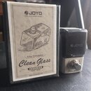 Na fotografii je kytarový pedál značky JOYO a jeho originální krabička. Na pedálu je viditelné logo JOYO a nápis Clean Glass. Krabička obsahuje nápis…