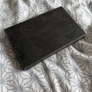 Černý obdélníkový pouzdro z texturovaného materiálu. V pravém dolním rohu je stříbrné logo s nápisem „Vandoren PARIS“. Povrch vykazuje mírné opotřebe…