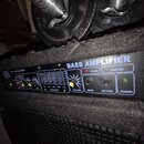 Černý basový zesilovač s nápisem BASS AMPLIFIER. Ovládací panel obsahuje sekci EQUALIZER s posuvníky, žlutý knoflík VOLUME a vstupy SEND a RETURN. Js…