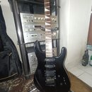 Černá elektrická kytara s prohnutým hmatníkem a dvěma humbuckery. Na hlavě krku je viditelné logo, které je však z tohoto úhlu nečitelné. Nástroj je…