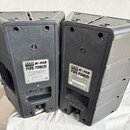 Dva černé plastové aktivní reproduktory v plastových krytech. Na zadní straně obou kusů je bílý štítek s nápisy DAR AUDIO, K-112 a PURE POWER!, dopln…