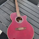 Akustická kytara s burgundy povrchem korpusu a hnědým hmatníkem. Uvnitř otvoru rezonanční skříně je vidět štítek s nápisy „Takamine“ a „G10“. Nástroj…