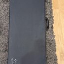 Černý obdélníkový kufřík s texturovaným povrchem. V dolní části je vyembosované logo Fender. Kufřík má na pravé straně plastovou rukojeť a v rozích k…