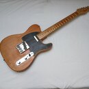 Elektrická kytara s přírodním dřevěným povrchem těla a hmatníkem. Na hlavě je viditelné logo Squier. Kytara má černý pickguard a dvě snímače, povrch…