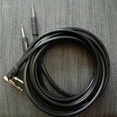 Černý instrumentální kabel s konektory typu 6,35 mm jack. Na jednom z konektorů je bílý nápis Fender a na kabelu se nachází bílá značka A20219. Kabel…