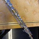 Zlatý mosazný sopránsaxofon s kovovými klapy a mechanismy. Na trubici je vidět nápis "YAMAHA". Nástroj vykazuje známky používání v podobě drobných šk…