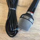 Černý dynamický mikrofon s kovovou stříbrnou mřížkou. Na těle je viditelný nápis D 501 a část loga značky. Vedle mikrofonu je srolovaný černý kabel,…