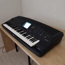 Černý digitální klavír s bílými a černými klávesami, umístěný na světlém dřevěném stole. Na levé straně korpusu je bílý nápis YAMAHA a vpravo nápis P…