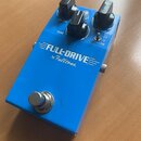 Modrý kytarový efekt pedál s nápisem FULL-DRIVE by Fulltone. Na horní straně jsou tři černé ovládací knoflíky s popisky VOLUME, TONE a OVERDRIVE a př…