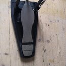 Fotografie znázorňuje basový pedál v černé a stříbrné barvě. Na spodní části pedálu je viditelné logo Roland. Konstrukce obsahuje kovové mechanismy a…